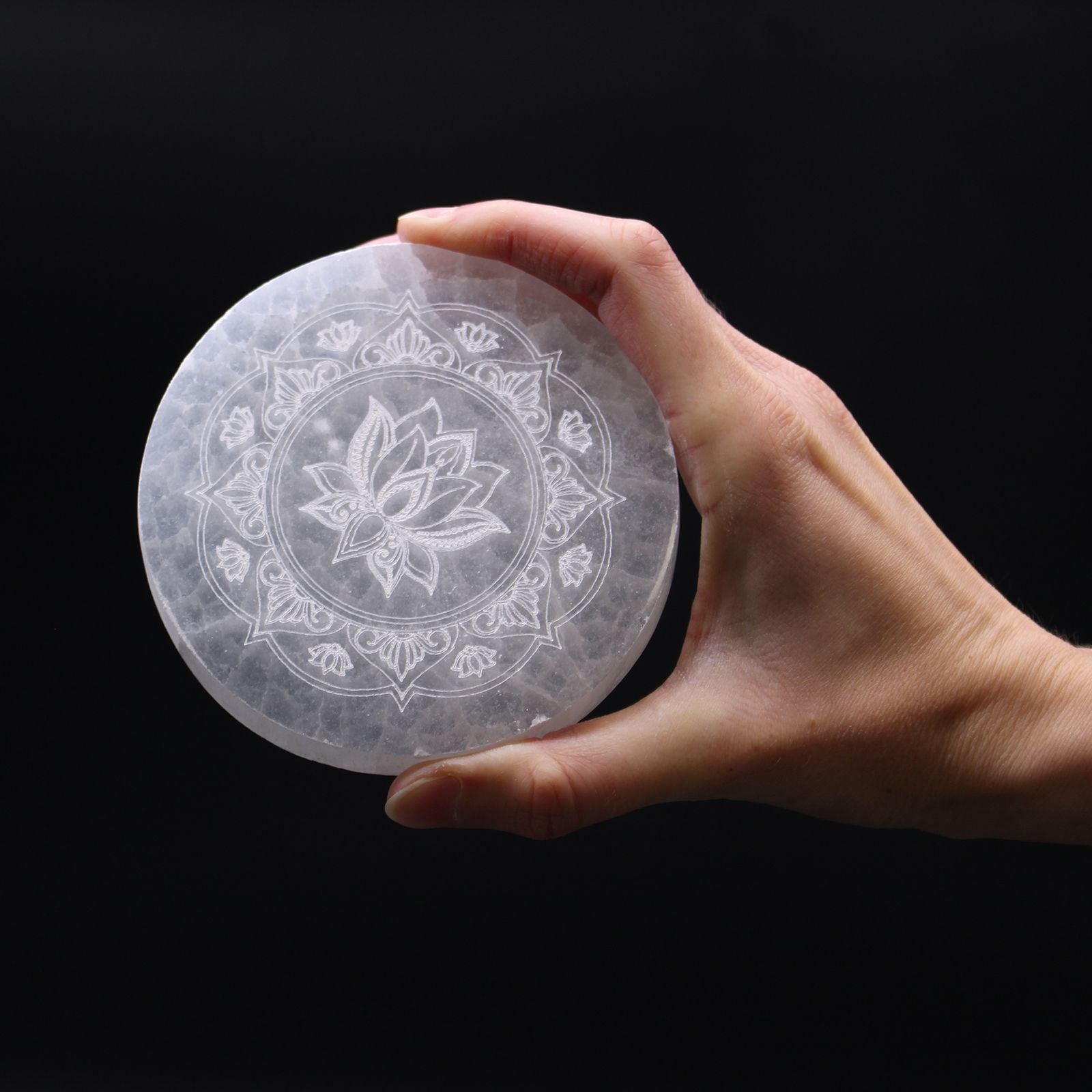 Plaque selenite lotus mandala tenue en main pour recharger les cristaux et harmoniser les energies