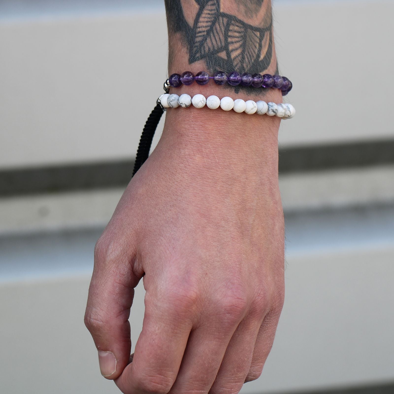 Bracelet améthyste porté au poignet au dessus d'un bracelet howlite blanche, bijoux en pierres naturelles élégant et ajustable