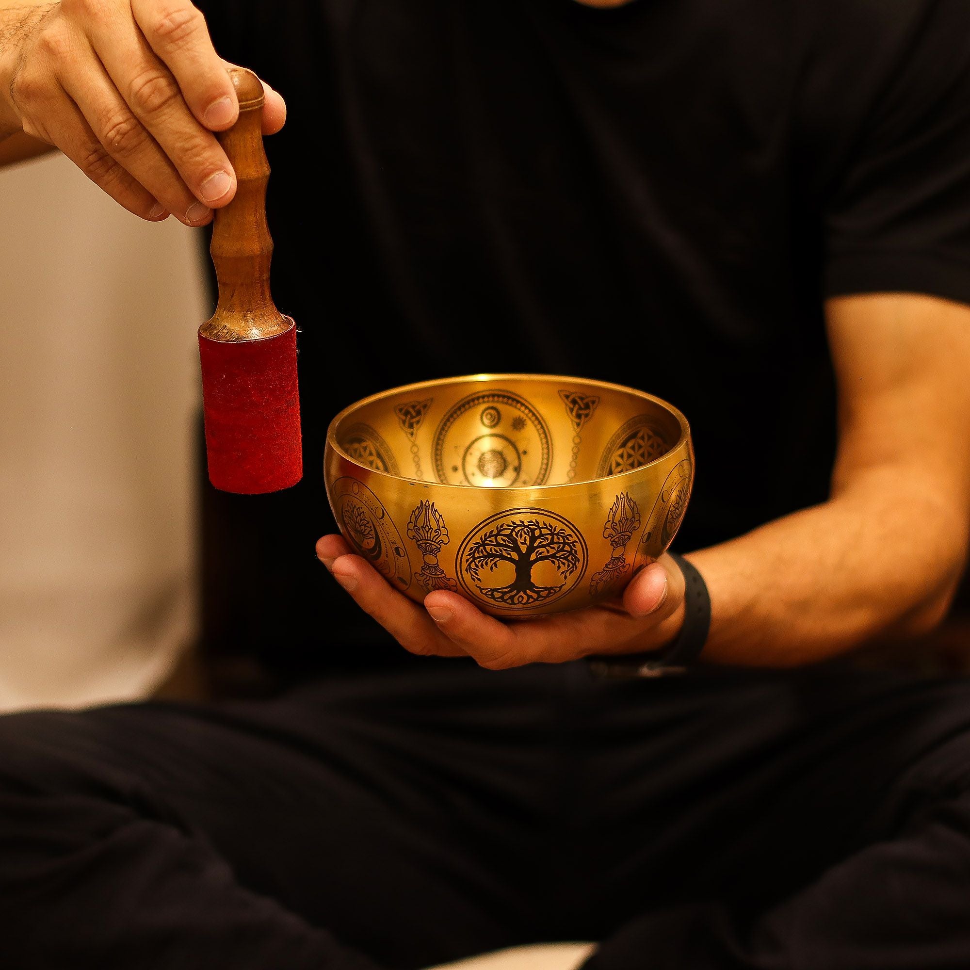 Personne utilisant un bol chantant tibétain avec un maillet pour produire des vibrations apaisantes