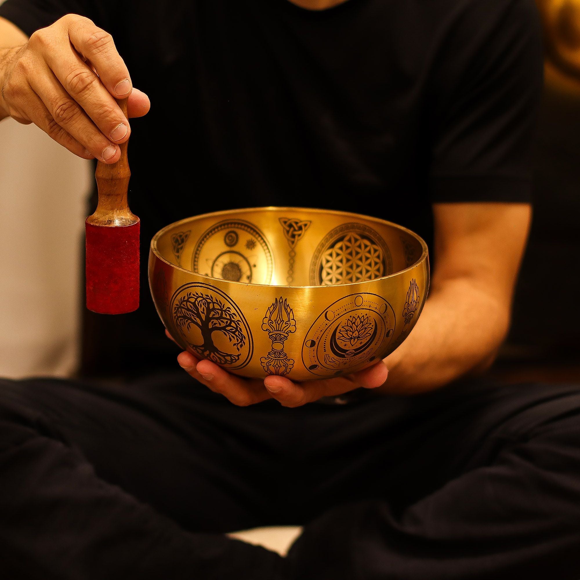 Personne utilisant un bol chantant tibétain avec un maillet pour produire des vibrations apaisantes