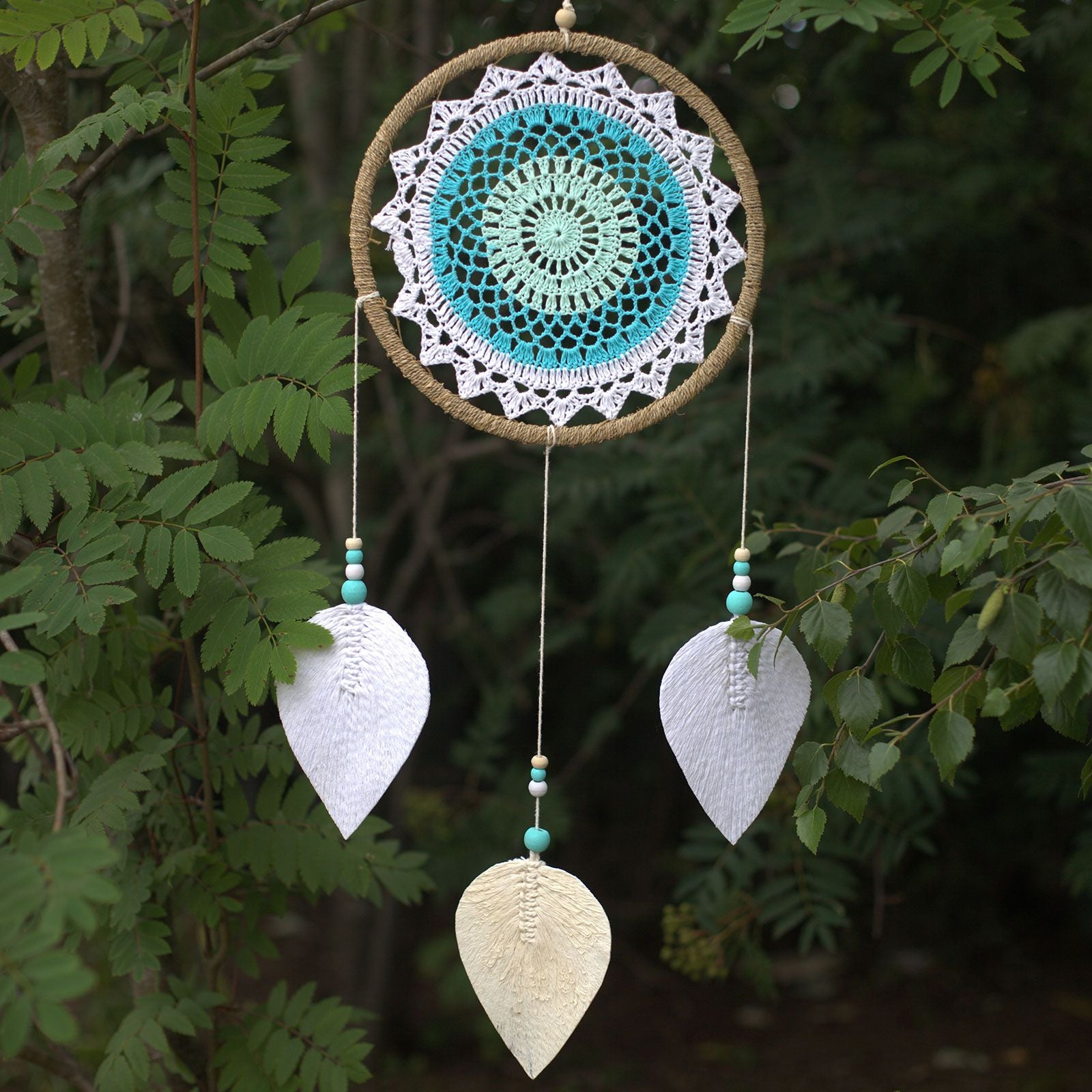 Attrape-rêves turquoise suspendu en extérieur, créant une atmosphère apaisante et fluide inspirée de la nature
