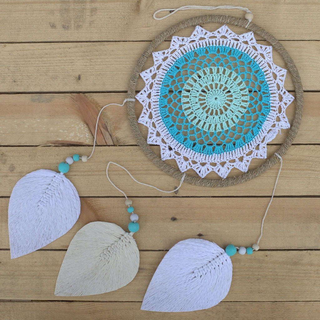 Attrape-rêves turquoise posé sur surface bois avec plumes blanches, idéal pour une décoration bohème apaisante