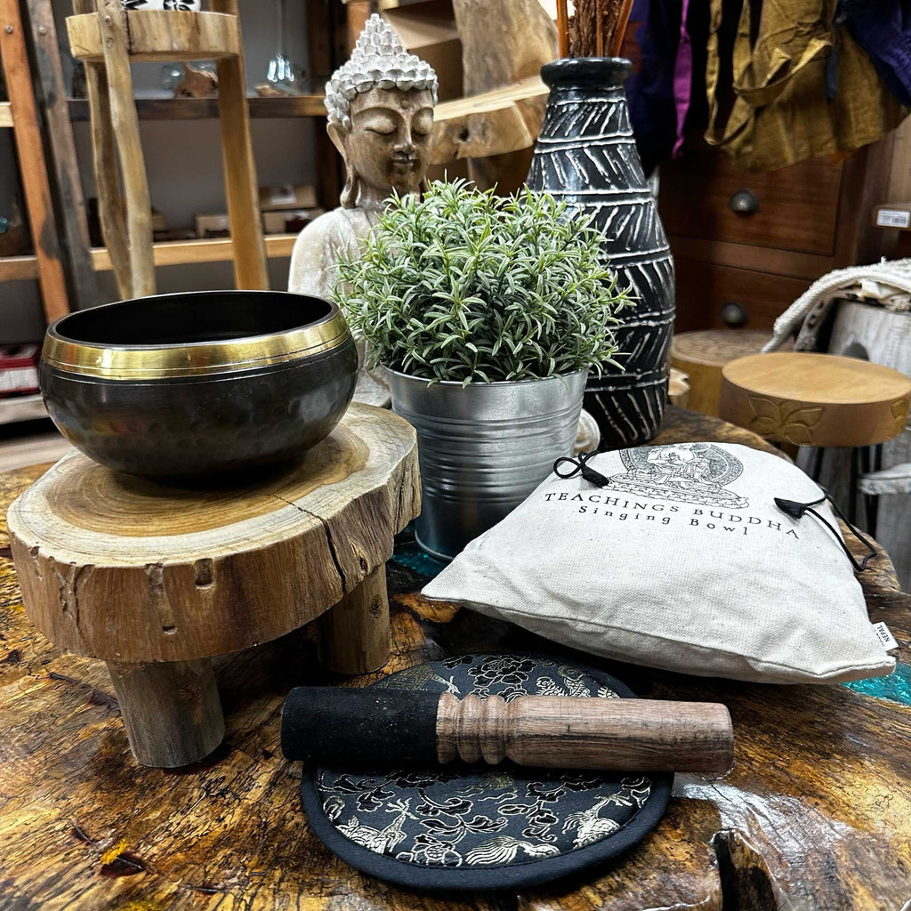 Bol chantant gravé green tara sur tabouret tronc avec accessoires sur surface naturelle, utilisé pour relaxation, méditation et équilibre énergétique