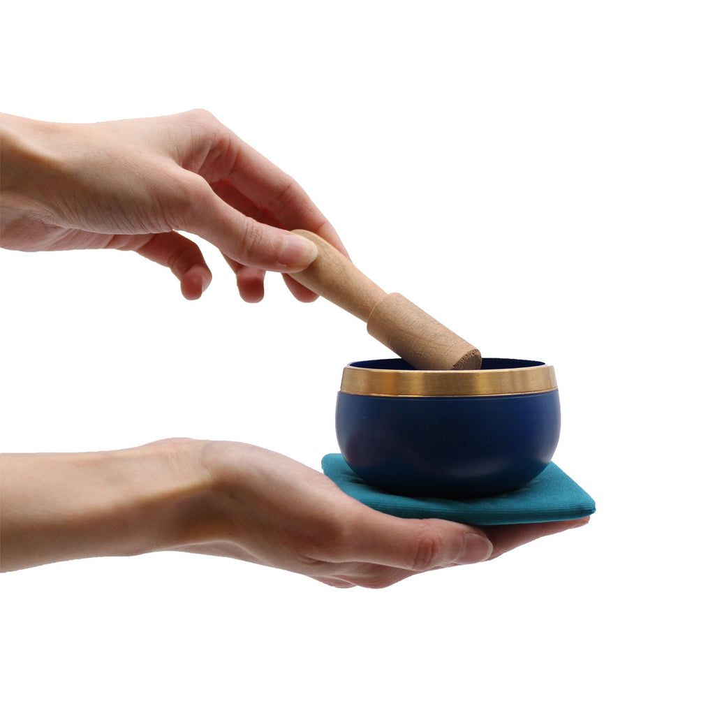 Main tenant un bol chantant chakra avec maillet en bois, utilisé pour relaxation et méditation