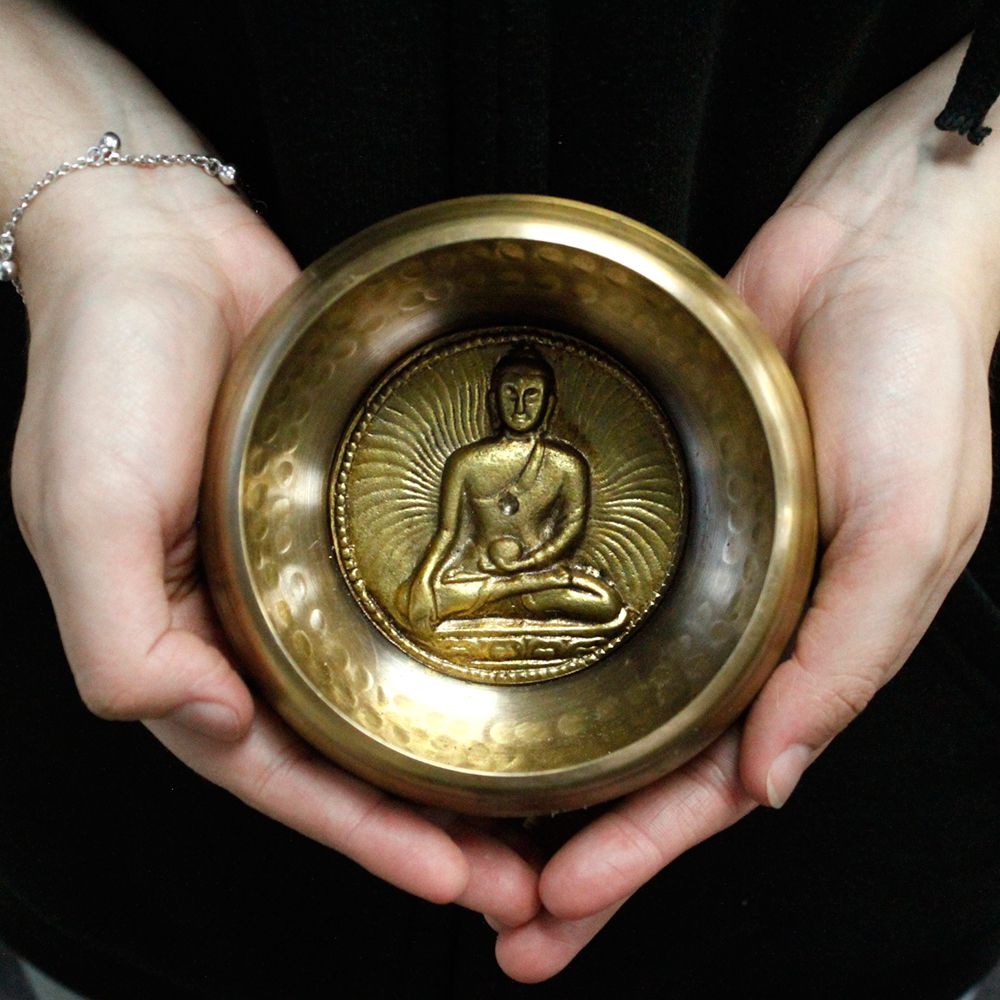 Bol chantant tibétain avec Bouddha medicine tenu dans les mains pour relaxation, méditation et harmonisation