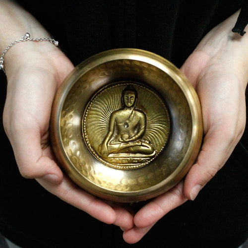 Bol chantant tibétain avec Bouddha medicine tenu dans les mains pour relaxation, méditation et harmonisation