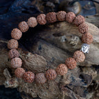 Bracelet en perles rudraksha avec tête de Bouddha posé sur bois ambiance méditation