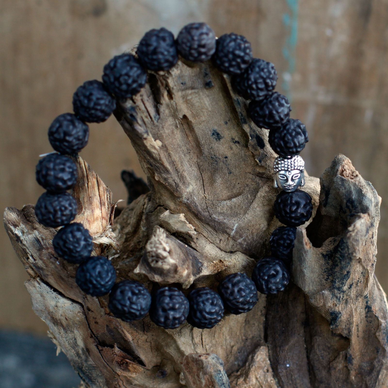 Bracelet en perles rudraksha avec tête de Bouddha posé sur bois ambiance méditation