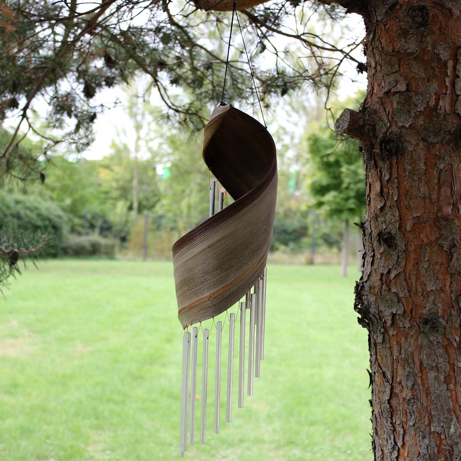 Carillon en feuille de coco naturel suspendu dans un jardin, ambiance naturelle et relaxante