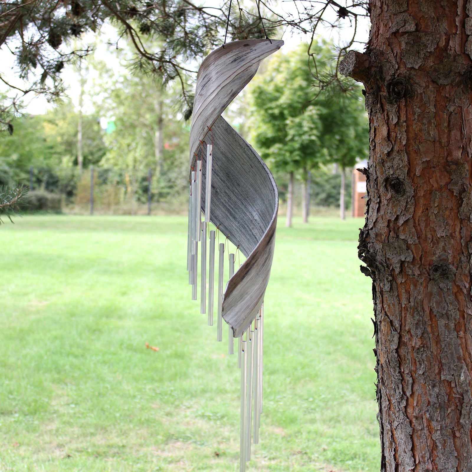 Carillon en feuille de coco whitewash suspendu dans un jardin, ambiance naturelle et relaxante