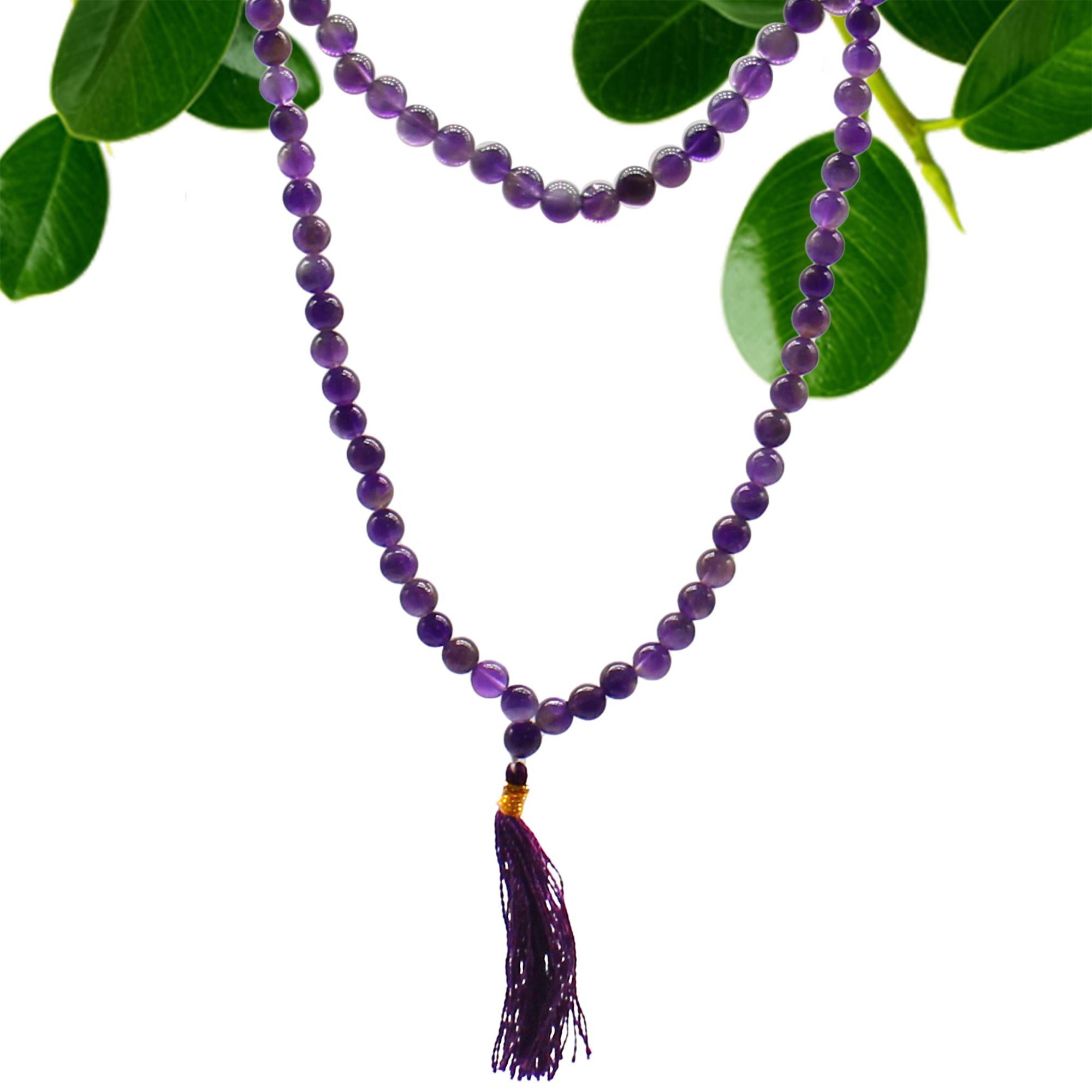 Collier mala 108 perles en pierre naturelle amethyste avec pompon violet, suspendu avec feuilles vertes en arriere plan, bijou spirituel pour meditation chakra et bien etre