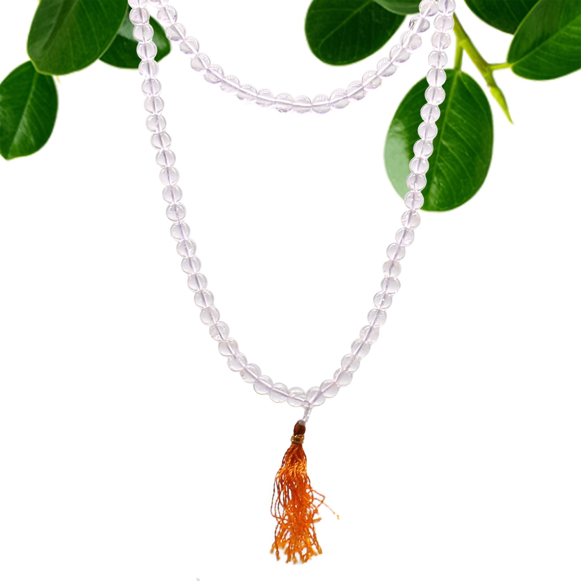 Collier mala 108 perles en pierre naturelle cristal de roche avec pompon cristal de roche, suspendu avec feuilles vertes en arriere plan, bijou spirituel pour meditation chakra et bien etre
