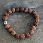Gros plan sur les perles de rudraksha et la tête de Bouddha du bracelet mala marron