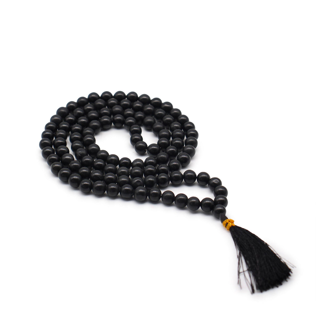 Mala 108 perles en pierre naturelle agathe noir avec pompon noir, collier de meditation en perles rondes pose sur fond blanc, bijou spirituel pour yoga et relaxation