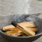 Bâton de Palo Santo en train de brûler avec fumée dans un bol pour purification et méditation