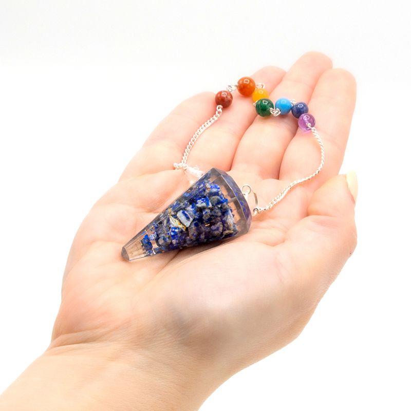 Pendule orgonite lapis lazuli tenu en main pour radiesthésie, divination et travail énergétique