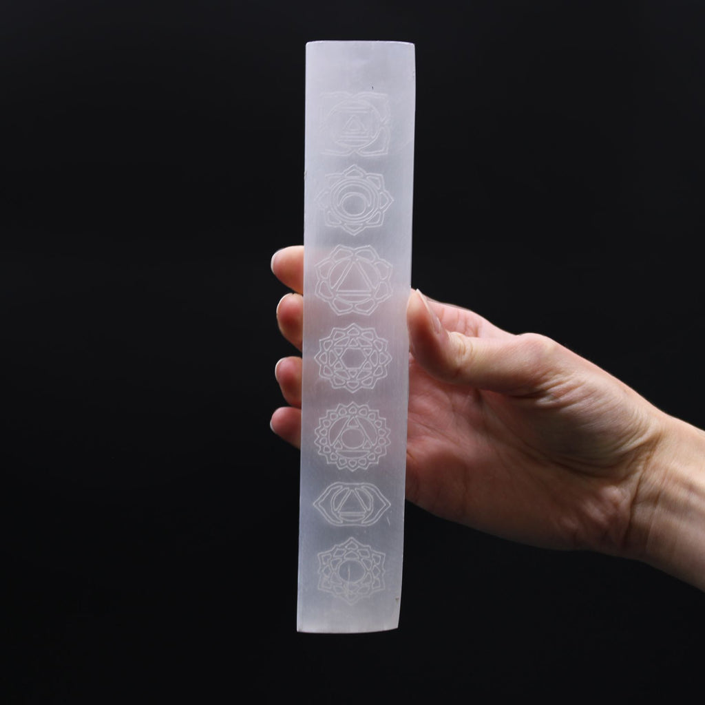 Plaque selenite chakras tenue en main pour recharger les pierres et equilibrer les energies du corps