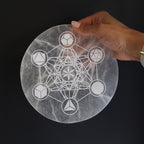 Plaque selenite geometrie sacree tenue en main pour recharger les pierres et harmoniser les energies spirituelles