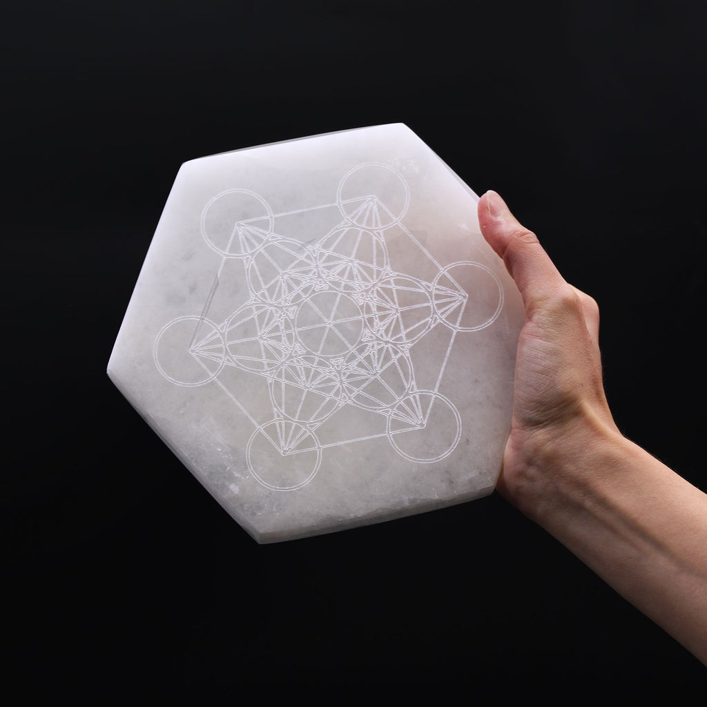 Plaque selenite hexagonale tenue en main pour recharger les pierres et favoriser clarte et concentration