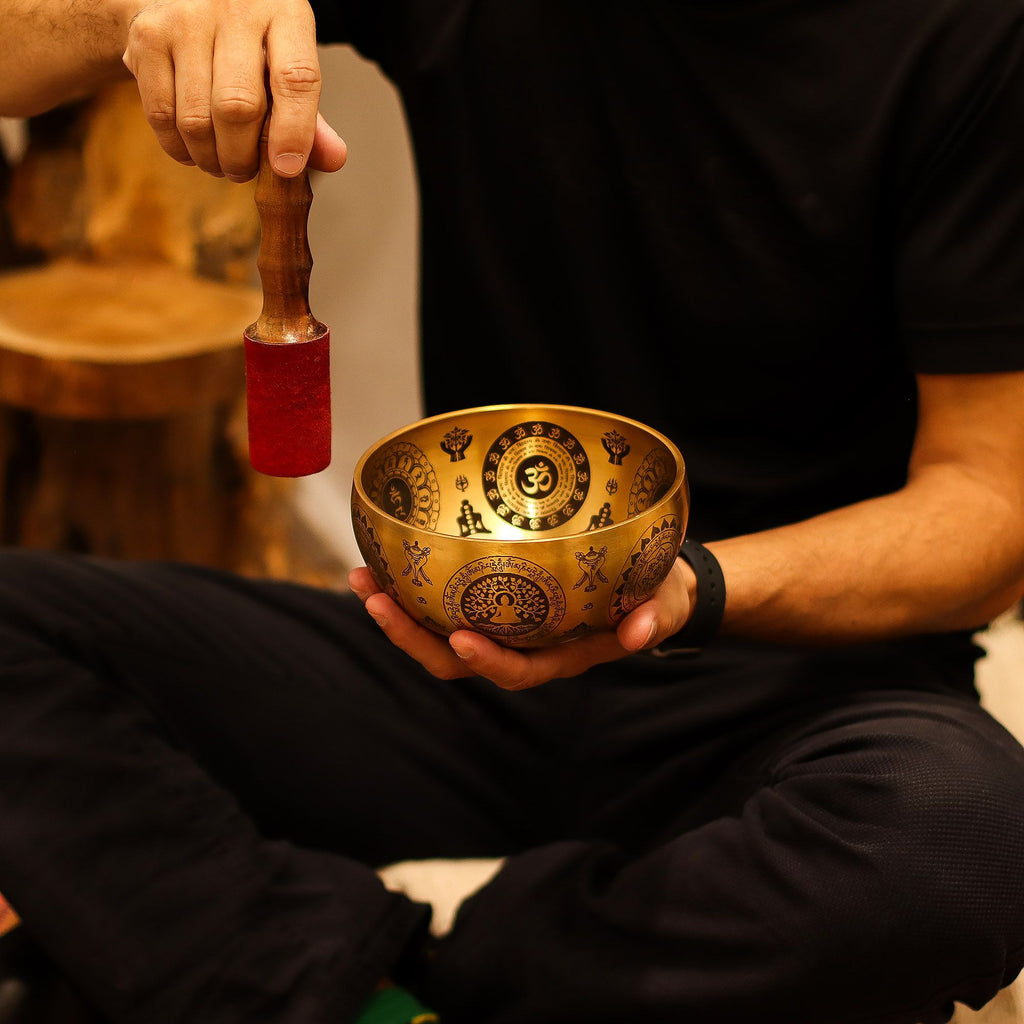 Personne utilisant un bol chantant tibétain avec maillet lors d’une séance de méditation et relaxation