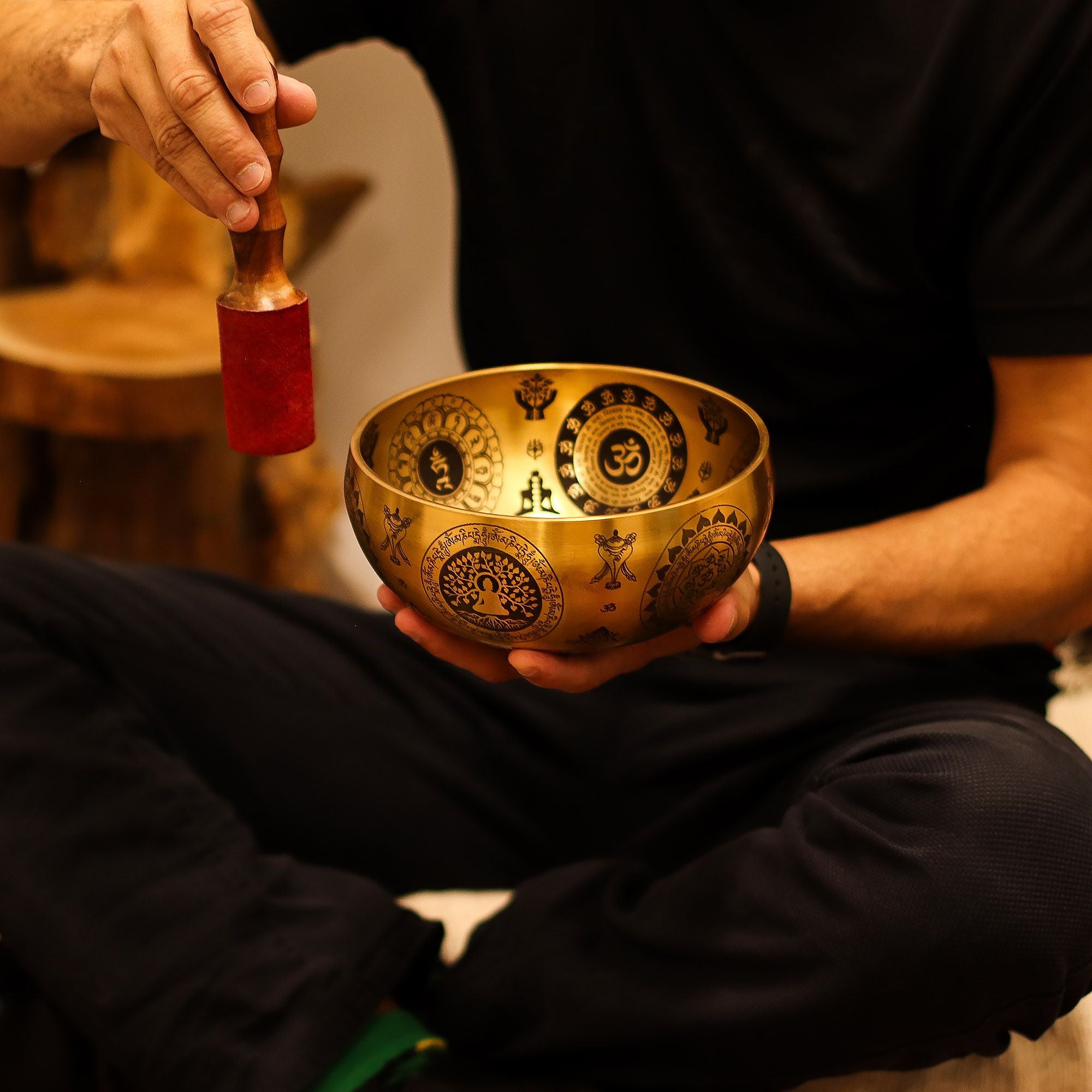 Personne utilisant un bol chantant tibétain avec maillet lors d’une séance de méditation et relaxation