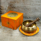 Bol chantant tibétain avec maillet posé à l’intérieur, coffret orange et coussin, kit complet de méditation