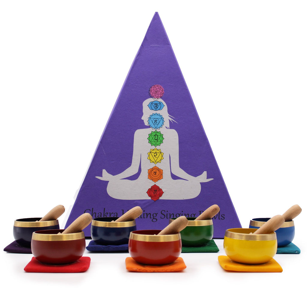 Bols chantants chakras colorés disposés devant un coffret pyramidal, parfait pour relaxation et équilibre énergétique