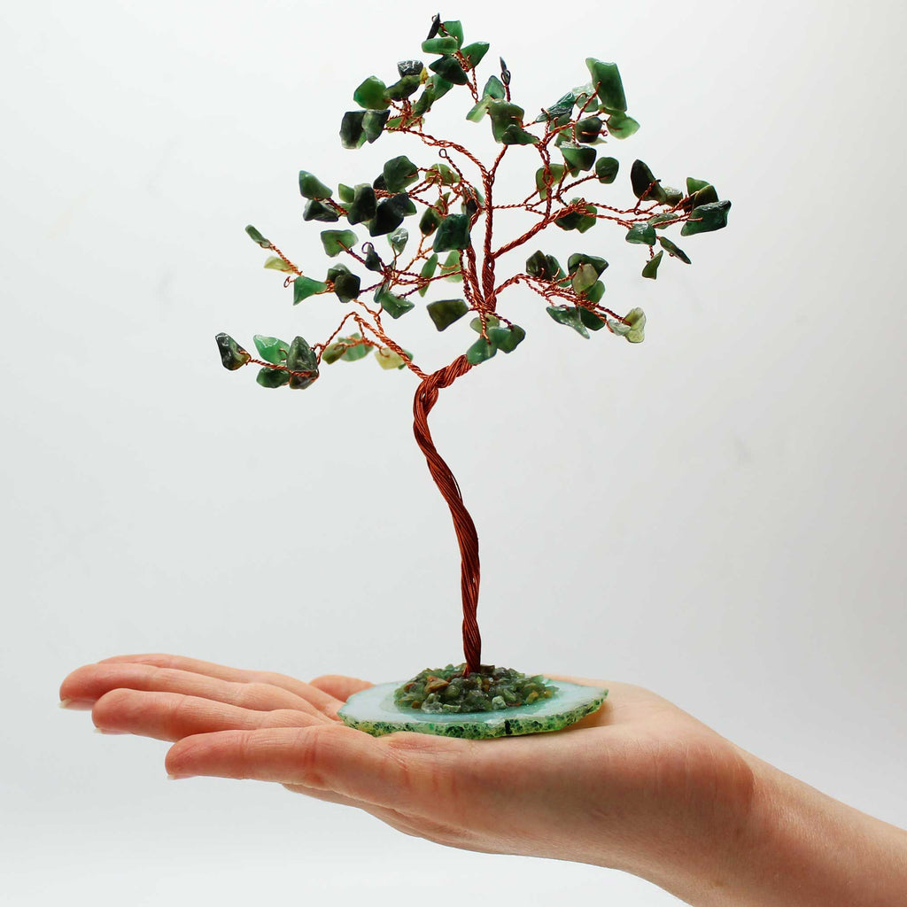 Arbre en aventurine posé dans une main avec pierres vertes naturelles et base minérale, objet énergétique décoratif