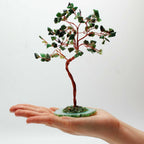 Arbre en aventurine posé dans une main avec pierres vertes naturelles et base minérale, objet énergétique décoratif