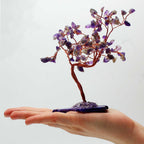 Arbre en améthyste tenu dans une main avec pierres naturelles violettes, symbole de calme et équilibre