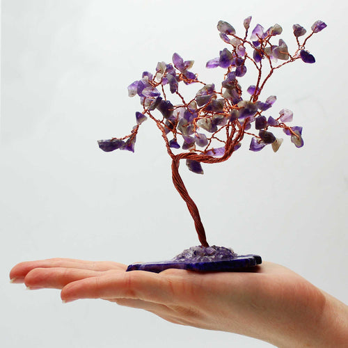 Arbre en améthyste tenu dans une main avec pierres naturelles violettes, symbole de calme et équilibre