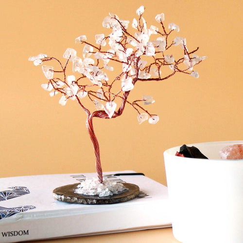 Arbre en pierres cristal de roche posé sur une table avec fond chaud, décoration énergétique minimaliste et apaisante