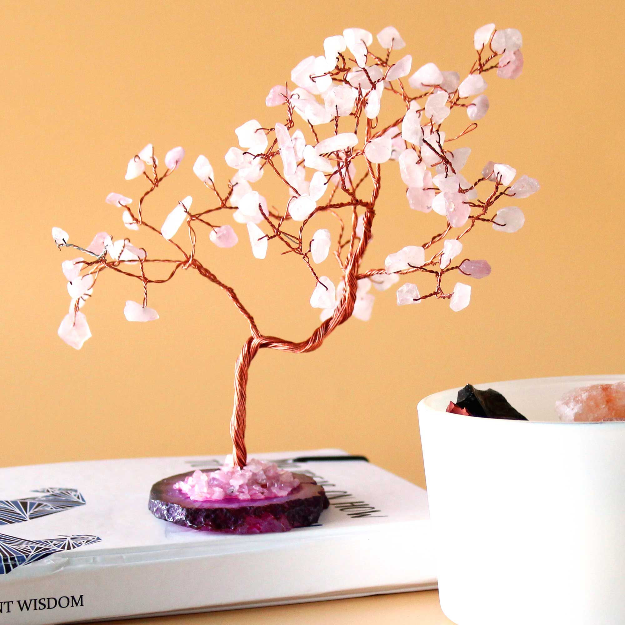 Arbre en quartz rose sur une surface avec fond chaud, objet décoratif spirituel aux énergies apaisantes