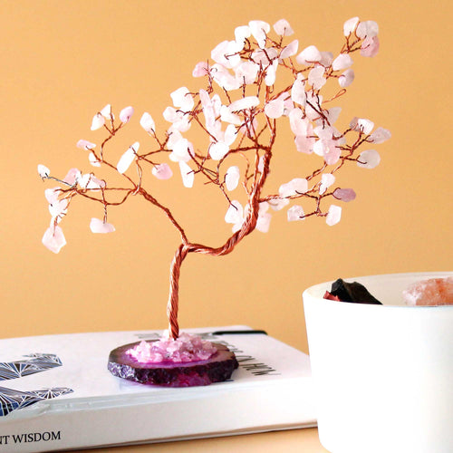 Arbre en quartz rose sur une surface avec fond chaud, objet décoratif spirituel aux énergies apaisantes