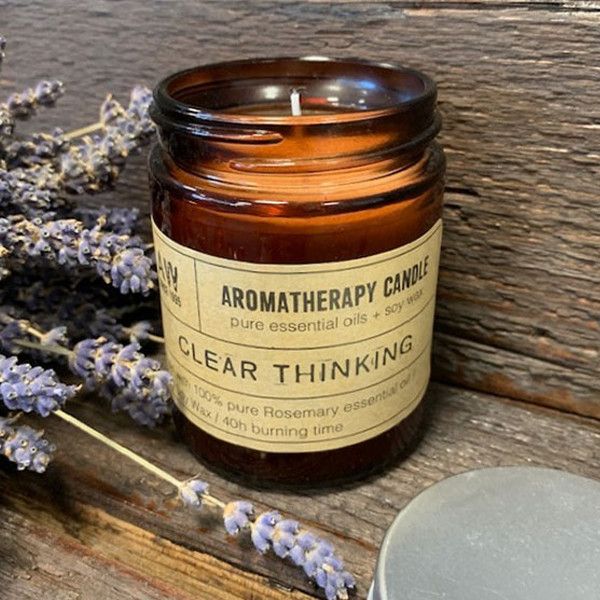 Bougie aromathérapie Clart mentale à base d’huile essentielle de romarin, posée sur une surface en bois avec des brins de lavande, ambiance naturelle et relaxante