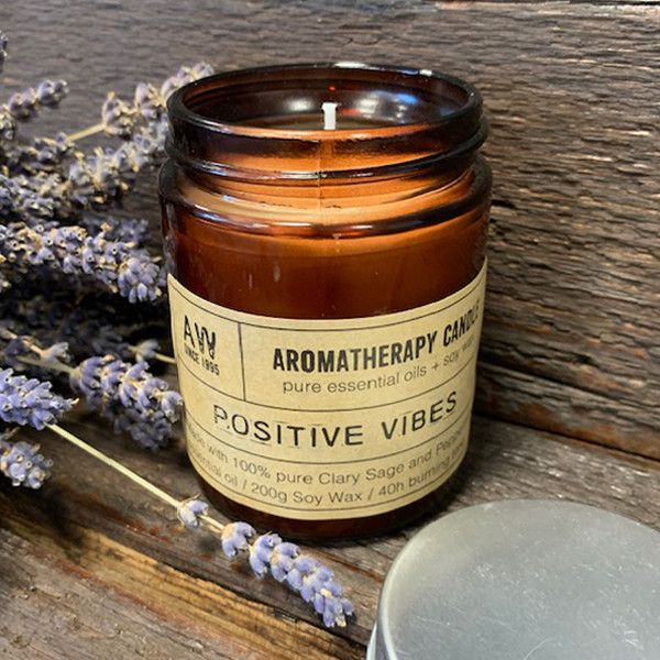 Bougie aromathérapie positive vibes à base d’huile essentielle de sauge sclarée et menthe, posée sur une surface en bois avec des brins de lavande, ambiance naturelle et relaxante