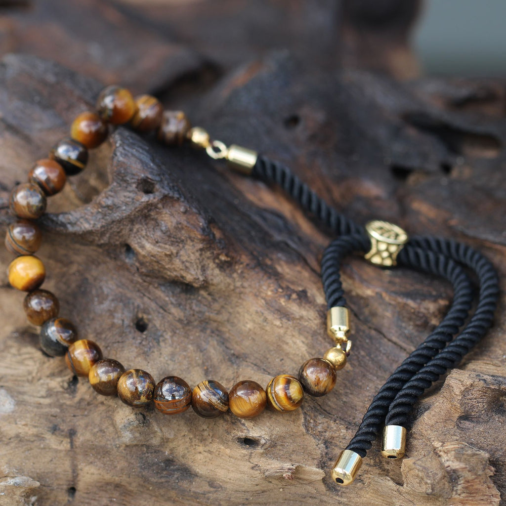 Bracelet en pierre naturelle oeil de tigre posé sur bois, symbole de sérénité et énergie spirituelle
