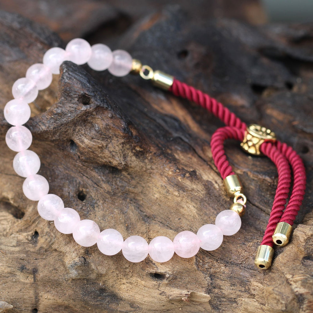 Bracelet en pierre naturelle quartz rose posé sur bois, symbole de sérénité et énergie spirituelle