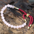 Bracelet en pierre naturelle quartz rose posé sur bois, symbole de sérénité et énergie spirituelle