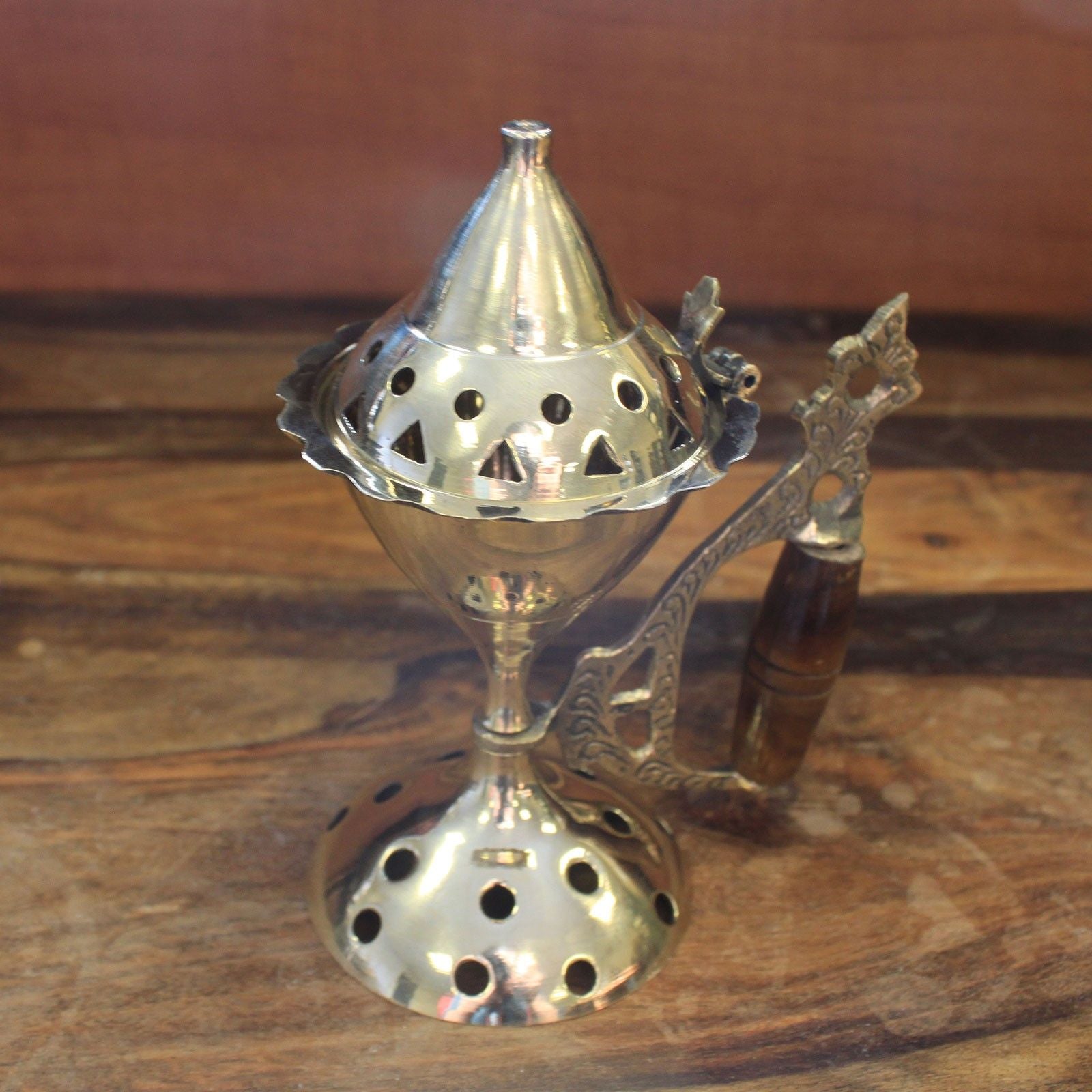 brûleur d’encens en laiton avec manche bois posé sur une table en bois avec encens pour créer une atmosphère apaisante
