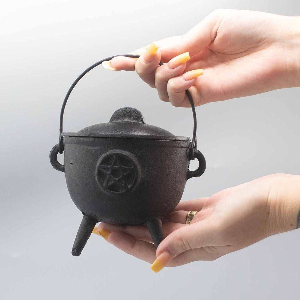 Chaudron rituel en fonte pentagramme tenu en main, utilisé pour rituels de protection et pratiques spirituelles