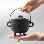 Chaudron rituel en fonte triple lune tenu en main, utilisé pour rituels énergétiques et pratiques spirituelles