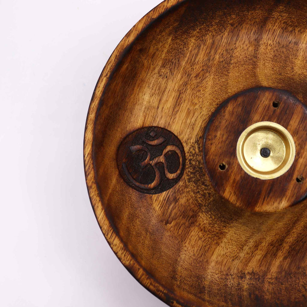 gros plan sur symbole om gravé dans un porte encens artisanal en bois naturel montrant la texture du bois et le support central pour encens