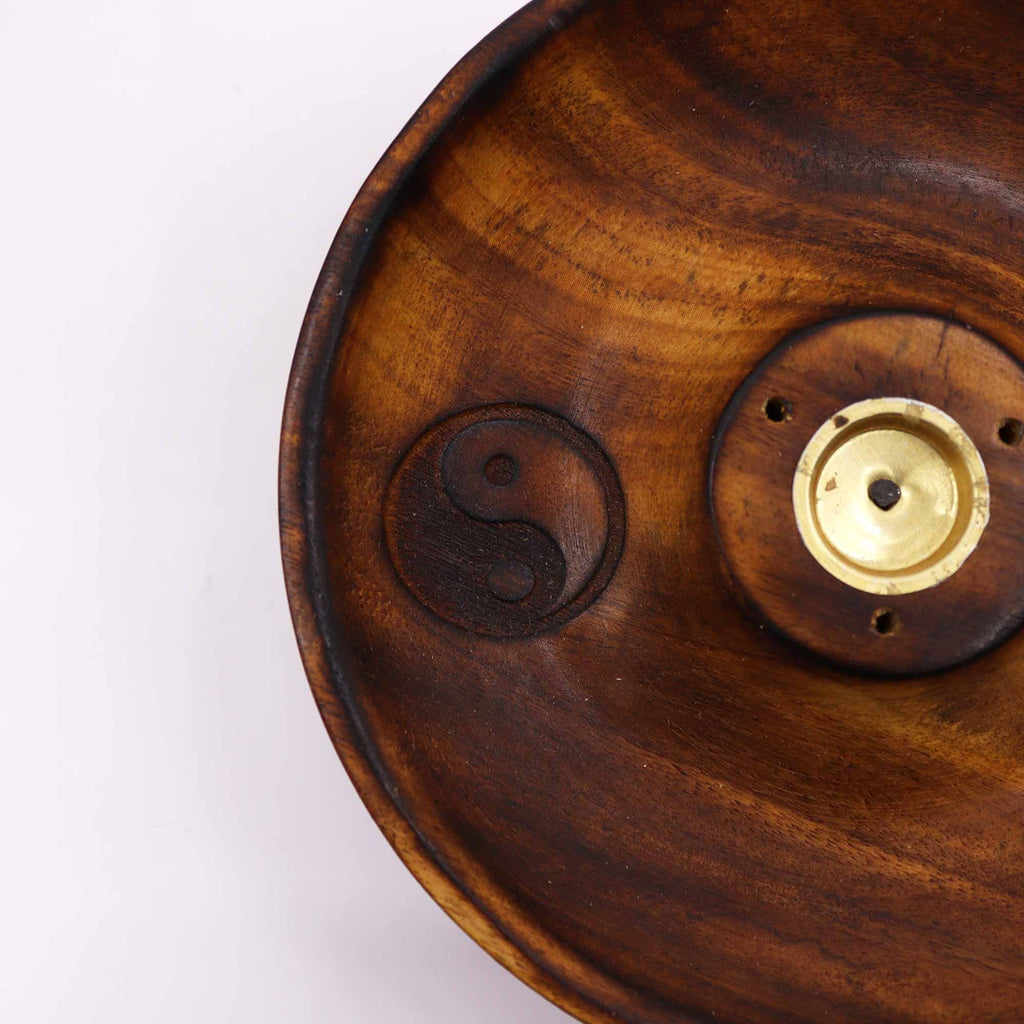 gros plan sur symbole yin yang gravé dans un porte encens artisanal en bois naturel montrant la texture du bois