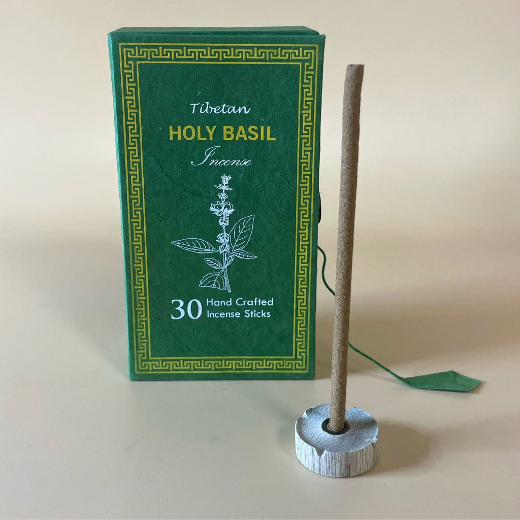 Encens tibétain basilic sacré avec bâtonnet posé sur support et coffret vert en arrière-plan