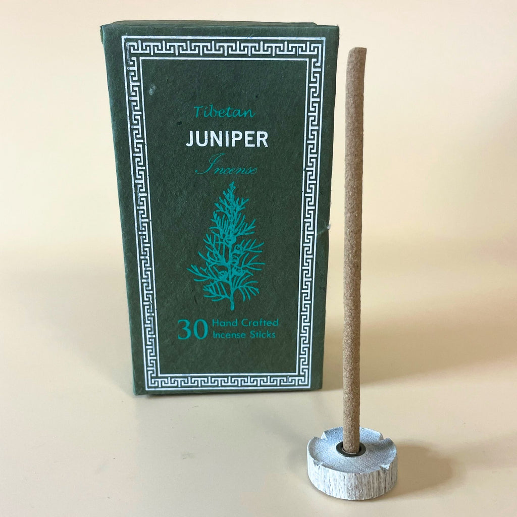 Encens tibétain genevrier avec bâtonnet posé sur support et coffret vert en arrière-plan