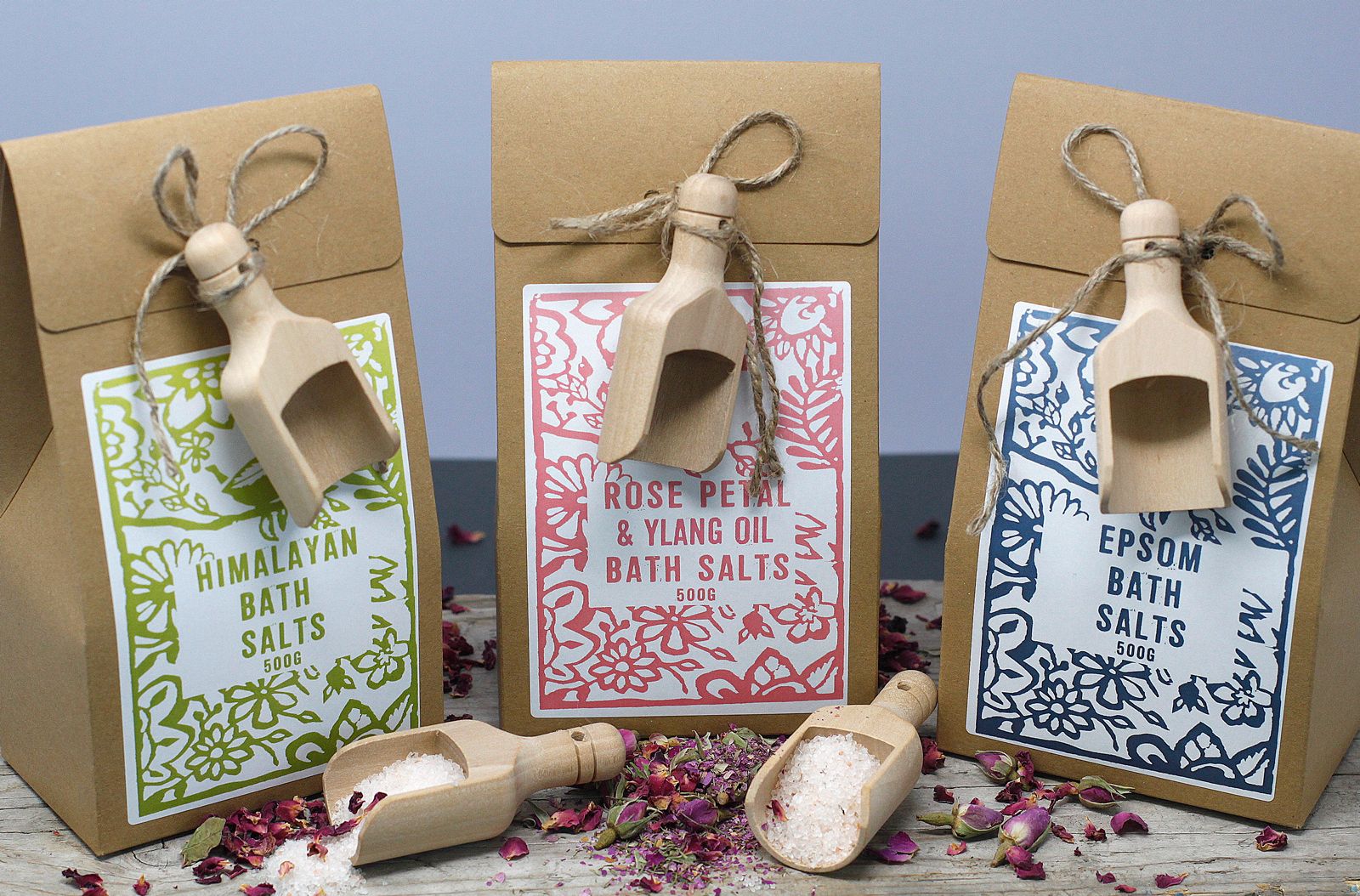 Trois sels de bain 500g Himalaya, rose ylang ylang et epsom alignés avec cuillères en bois et ambiance bien-être