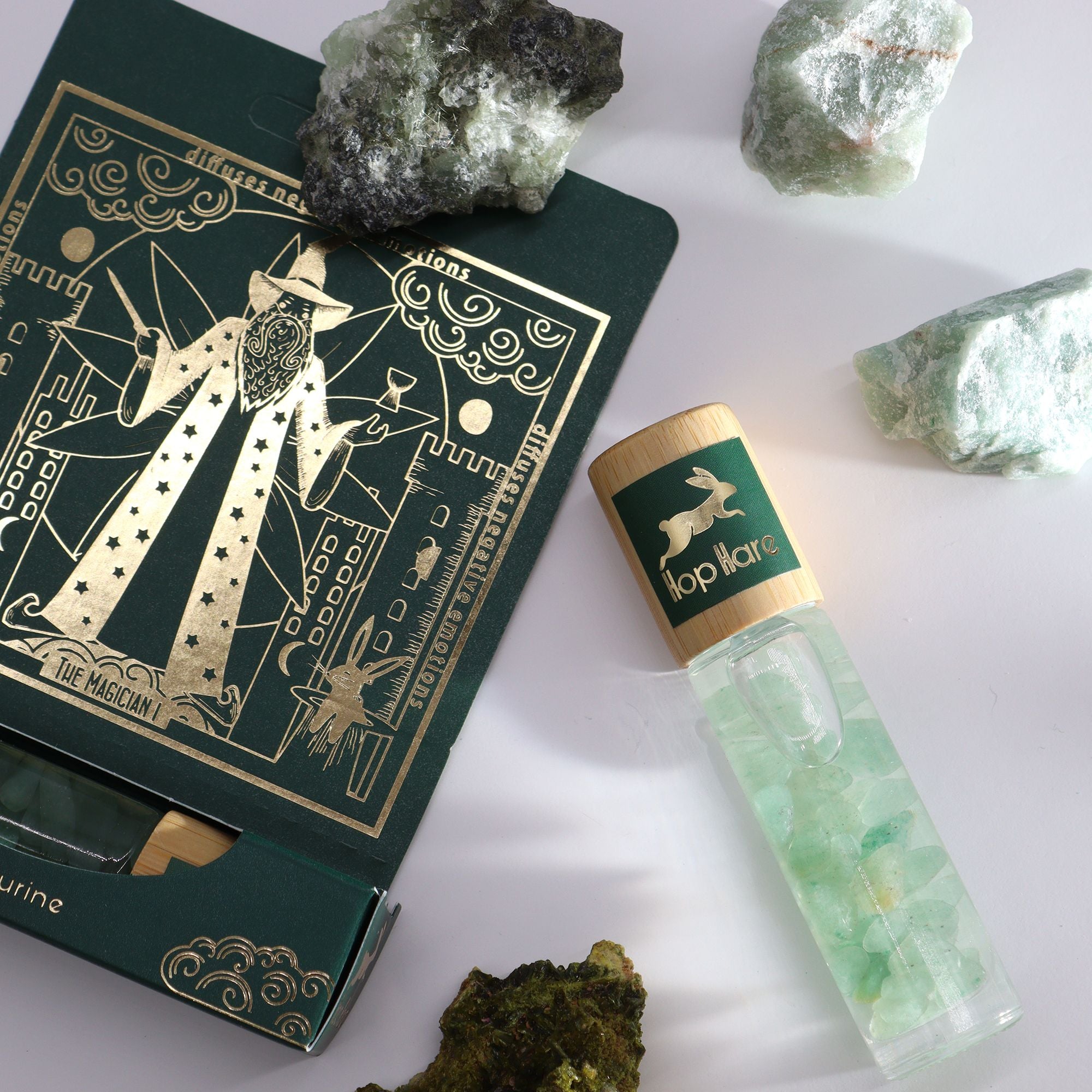 Roll-on Le magicien aux huiles essentielles et pierre naturelle d’aventurine posé sur son coffret tarot.