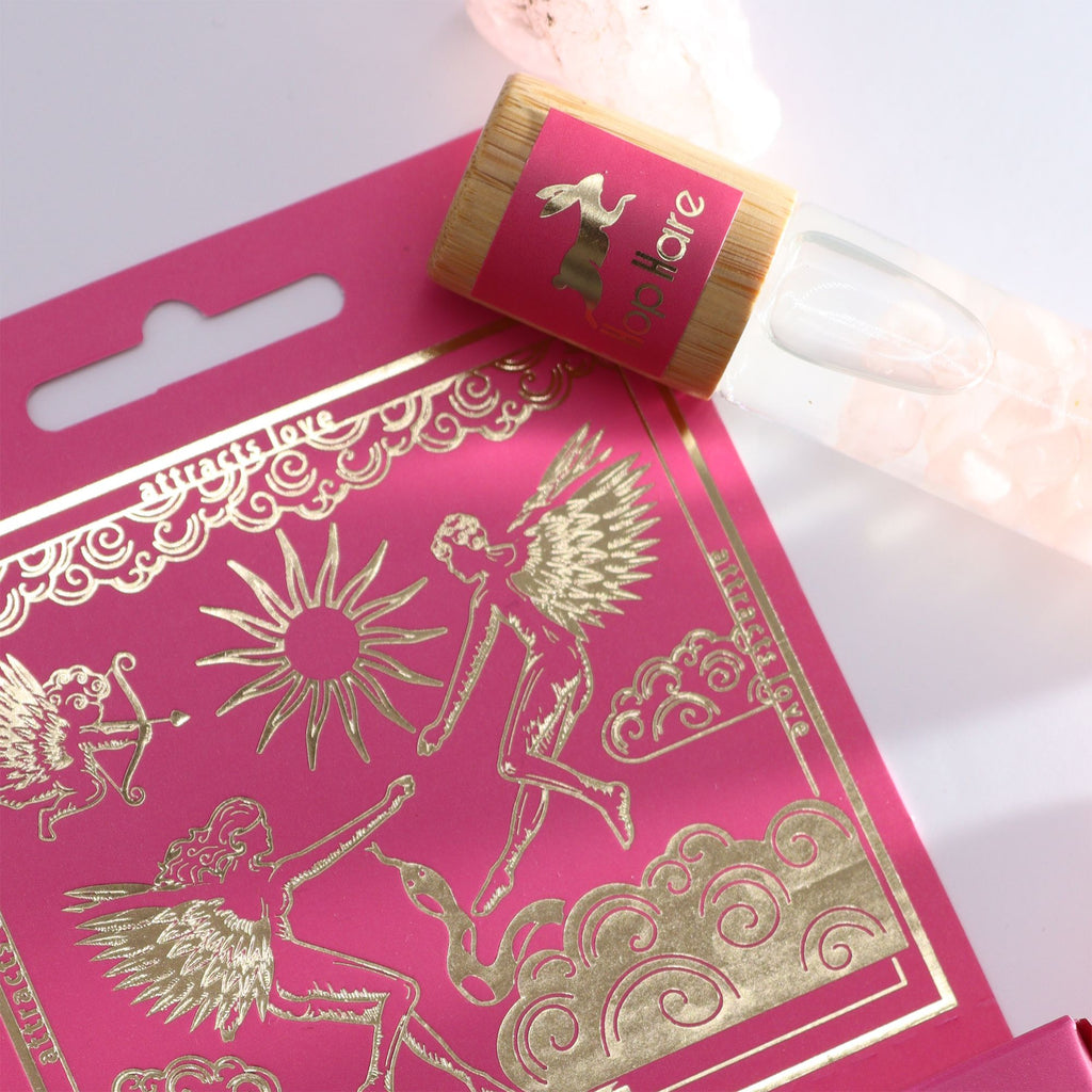 Roll-on Les amoureux aux huiles essentielles et pierre naturelle de quartz rose posé sur son coffret tarot.