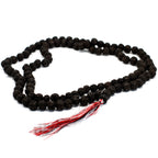 Vue complète d’un mala en rudraksha composé de 108 perles foncé avec pompon rouge et blanc sur fond clair.
